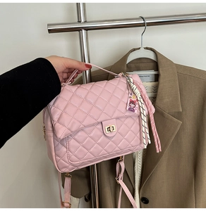 Detail of pink quilted leather bag showing gold twist lock and woven rope charm decor