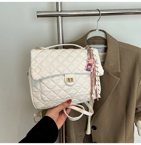 Detail of white quilted tote bag with gold twist lock and a pink decorative charm