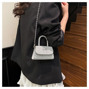 Detail of silver glitter crossbody bag with metallic bow and elegant chain strap