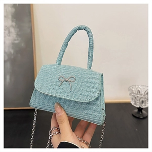 Detail of light blue glitter mini handbag featuring a silver metal butterfly bow and chain