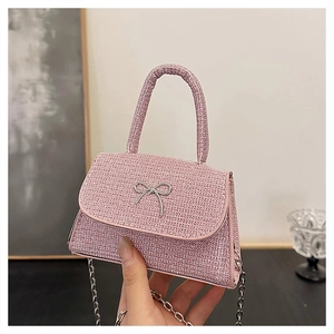 Detailed macro view of pink glitter fabric and metallic bow on mini handbag