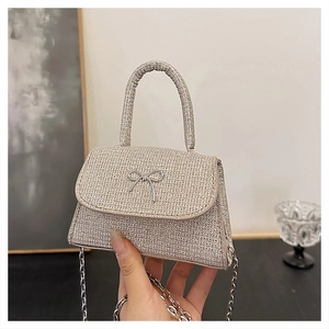 Detailed close-up of a silver sequined handbag featuring a metallic bow and chain strap