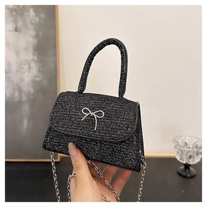 Close-up of small black glitter handbag with silver butterfly knot and chain strap