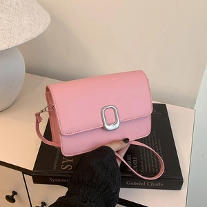 Minimalist light pink crossbody square bag with silver metal buckle on a desk