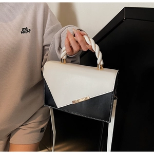 Detail of a color-block small square bag with braided leather handle and golden metal bar