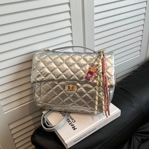Silver quilted tote bag with chain strap and metallic finish on white book background