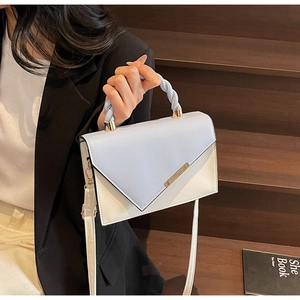 Detail of blue and white contrast leather bag with spiral rope handle and gold metal links