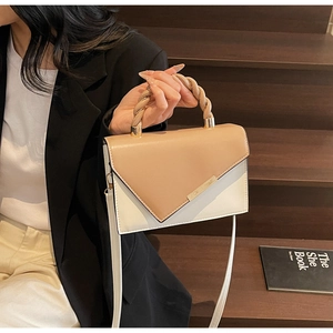 Detail of two-tone crossbody bag featuring braided handle and stylish metallic accents