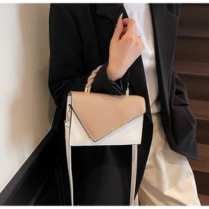 Detail of color-block crossbody bag with asymmetric flap and gold metal bar accent