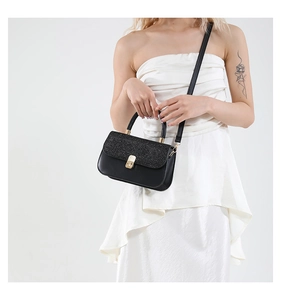 Detail of black glitter flap crossbody bag with gold metal lock and leather strap