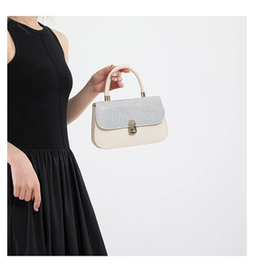 Detailed shot of shimmering sequined flap and silver metal clasp on cream crossbody bag
