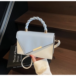 Close-up of color-block crossbody bag with spiral twisted handle and gold buckle detail
