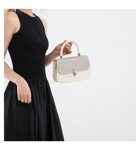Close-up of elegant cream white handbag featuring silver sequins and gold metallic lock