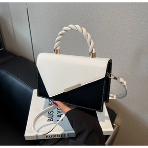Detail of contrast color handbag with woven handle and gold metal buckle on leather