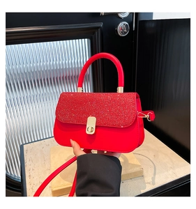 Close-up of red leather handbag featuring glitter panel and golden metal turn-lock