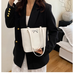 Détail du cabas blanc avec un nœud métallique argenté élégant et texture en cuir