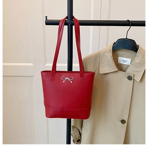 Détail du sac cabas en cuir ciré rouge avec breloque nœud argenté et doubles bretelles