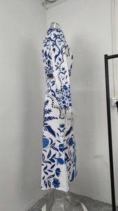 Detailed view of blue floral porcelain pattern on a white long sleeve maxi dress