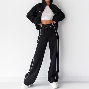 Women's black lounge set featuring a zip-up cropped jacket and white striped track pants