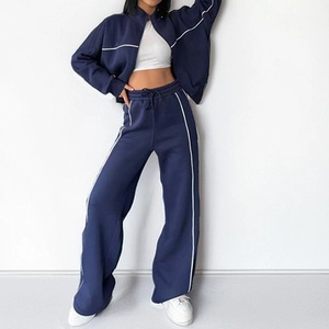 Navy blue two-piece tracksuit with zip-up jacket and wide-leg joggers featuring white piping