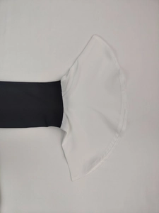 Close-up of elegant black dress sleeve featuring contrasting white flared ruffle cuff