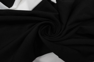Close-up of premium black knitted fabric texture with soft drape and spiral pattern