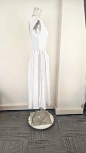 Détail latéral de la robe blanche sans manches avec taille cintrée et jupe plissée
