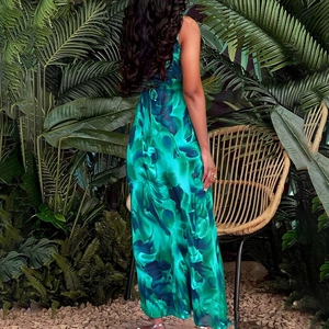 Back view of elegant tropical floral print sleeveless maxi dress in a resort setting