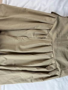 Gros plan détaillé d'une robe longue kaki montrant la texture plissée et les coutures