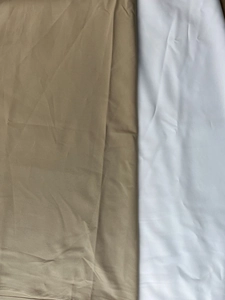 Gros plan détaillé du tissu soyeux kaki et blanc montrant la qualité des coutures fines