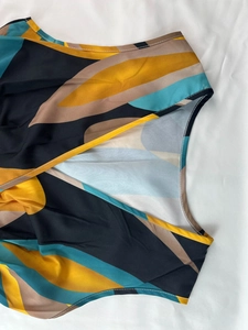 Detail of V-neckline and sleeveless armhole with yellow piping and abstract geometric print