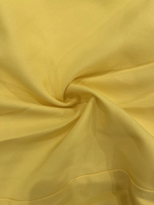 Detail shot of bright yellow fabric texture with elegant spiral pleated draping