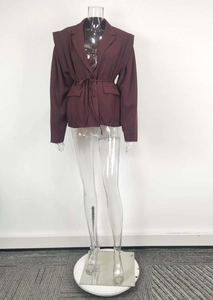 Detail of burgundy long sleeve blazer jacket featuring waist tie and flap pockets