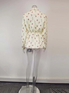 Back view of cream floral blazer featuring a cinched waist and delicate pink flower print