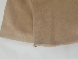 Close-up of khaki knitted jacket fabric showing fine vertical texture and neat stitching