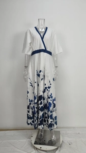 Detail view of the elegant V-neckline and high waist blue trim on the white floral maxi dress
