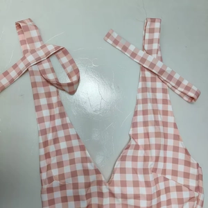 Detail of pink gingham halter dress with V-neckline and tie straps on grey background