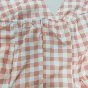 Detailed close-up of pink and white gingham halter dress showing the V-neck and zipper