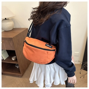 Rear view of model wearing an orange nylon crescent crossbody bag with adjustable strap