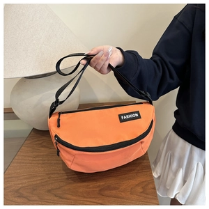 Detail of bright orange crescent messenger bag with fashion label and adjustable strap