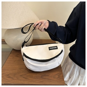 Gros plan du sac demi-lune en nylon blanc avec sangle noire et étiquette FASHION