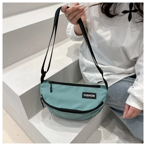 Detail of mint green nylon crescent bag featuring black zippers and fashion label