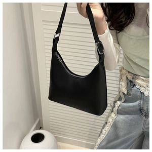 Detail of a minimalist black faux leather shoulder bag featuring silver hardware and a hobo shape