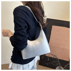 Silver metallic hobo bag worn by a model in a minimalist modern indoor setting
