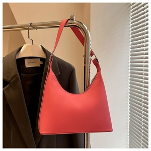 Minimalist pink leather shoulder bag with sleek curved design on a display rack