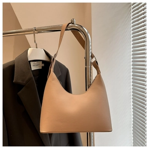 Close-up of beige hobo underarm bag hanging on a rack with soft side lighting