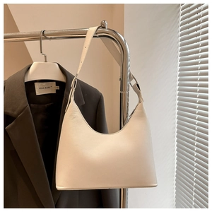 Detail of off-white leather underarm bag with adjustable strap in a modern office setting