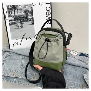 Detail of olive green nylon crossbody bag with drawstring closure and adjustable strap
