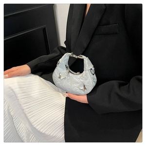 Détail du sac demi-lune plissé bleu clair avec breloques papillon et poignée en chaîne