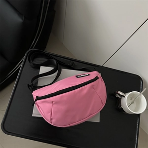 Pink canvas crossbody bag with black straps and fashion label for casual outdoor wear